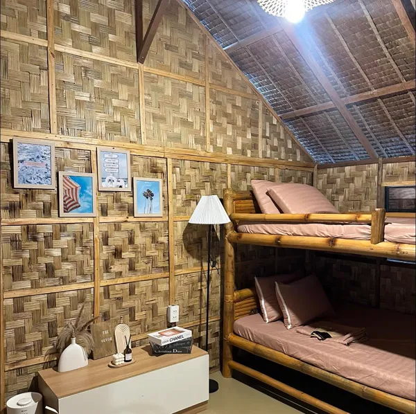 Bamboo bunk beds with pink cushions, a floor lamp, and framed prints.