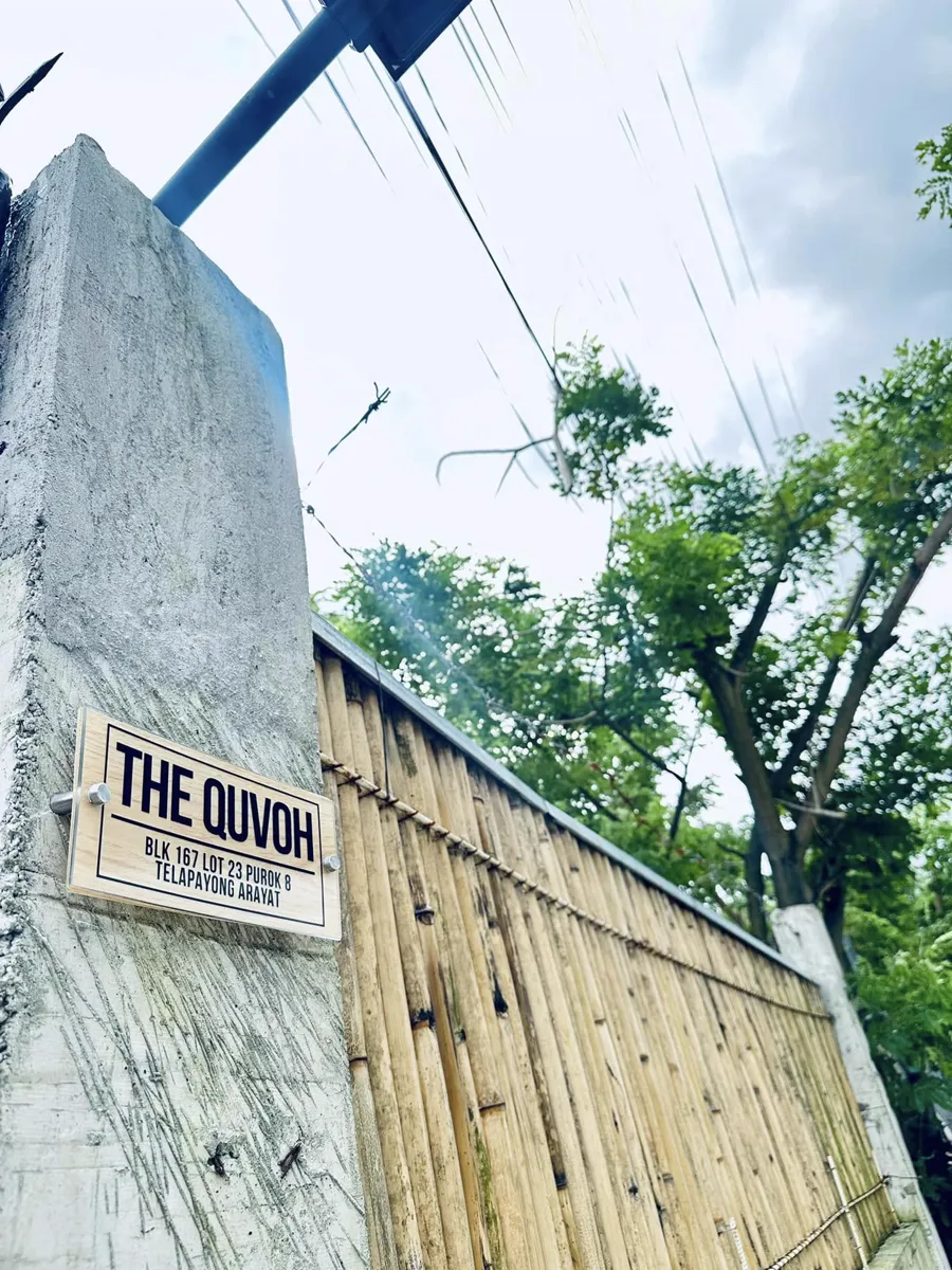 The Quvoh sign on a concrete post beside the bamboo fence.