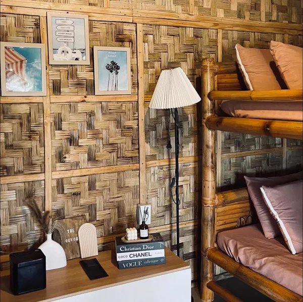 Bamboo bed frame beside a shelf with a lamp and decor.
