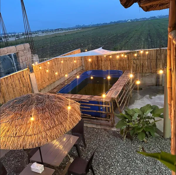 The private pool at dusk with string lights and fields beyond the fence.