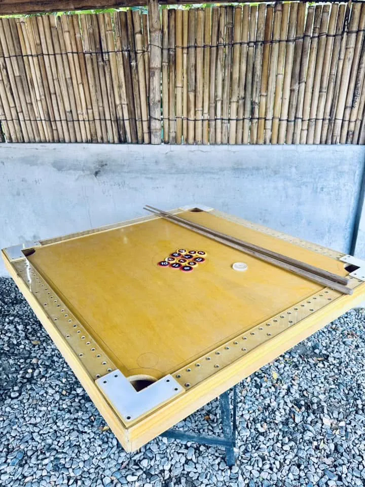 A yellow poolan game table on the courtyard gravel.