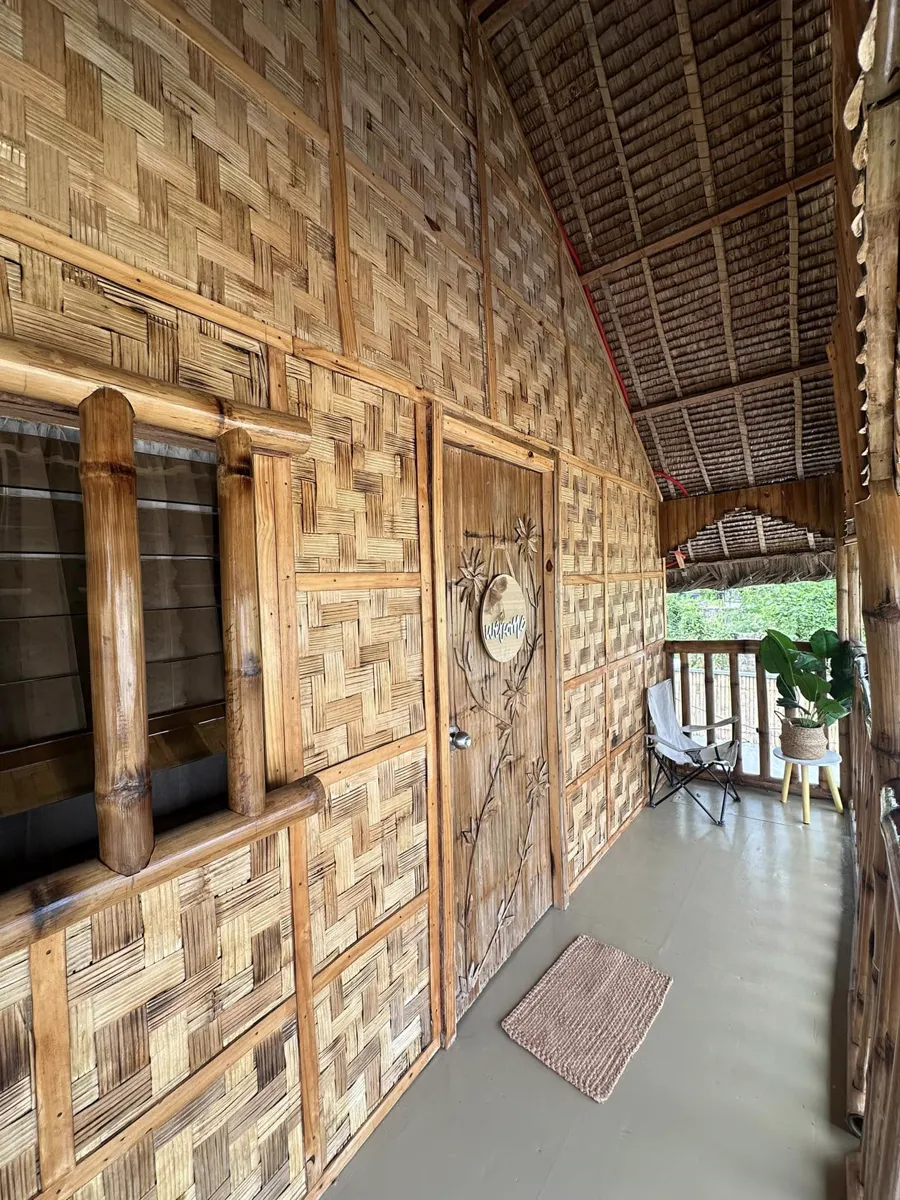 Veranda corridor with woven bamboo walls and a carved wooden door.